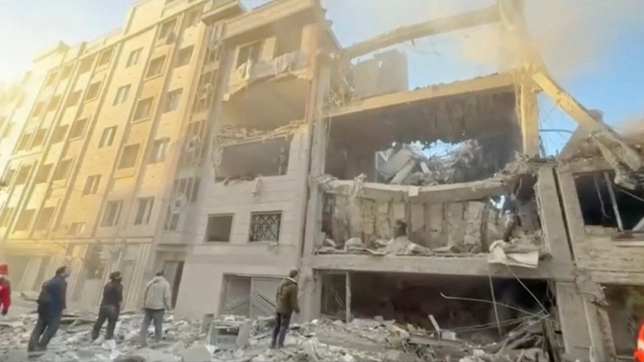 People stand near damaged buildings, amid the U.S.-Israeli conflict with Iran, in Tehran, Iran, in this still image obtained from a handout video released on April 1, 2026.    Iranian Red Crescent Society/Handout via REUTERS