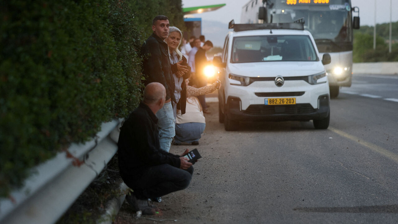 FILE PHOTO: People gather on the side of a road seeking protection as a rocket volley from Iran flies overhead, amid the U.S.-Israeli conflict with Iran, in northern Israel, March 17, 2026. REUTERS/Ammar Awad/File Photo