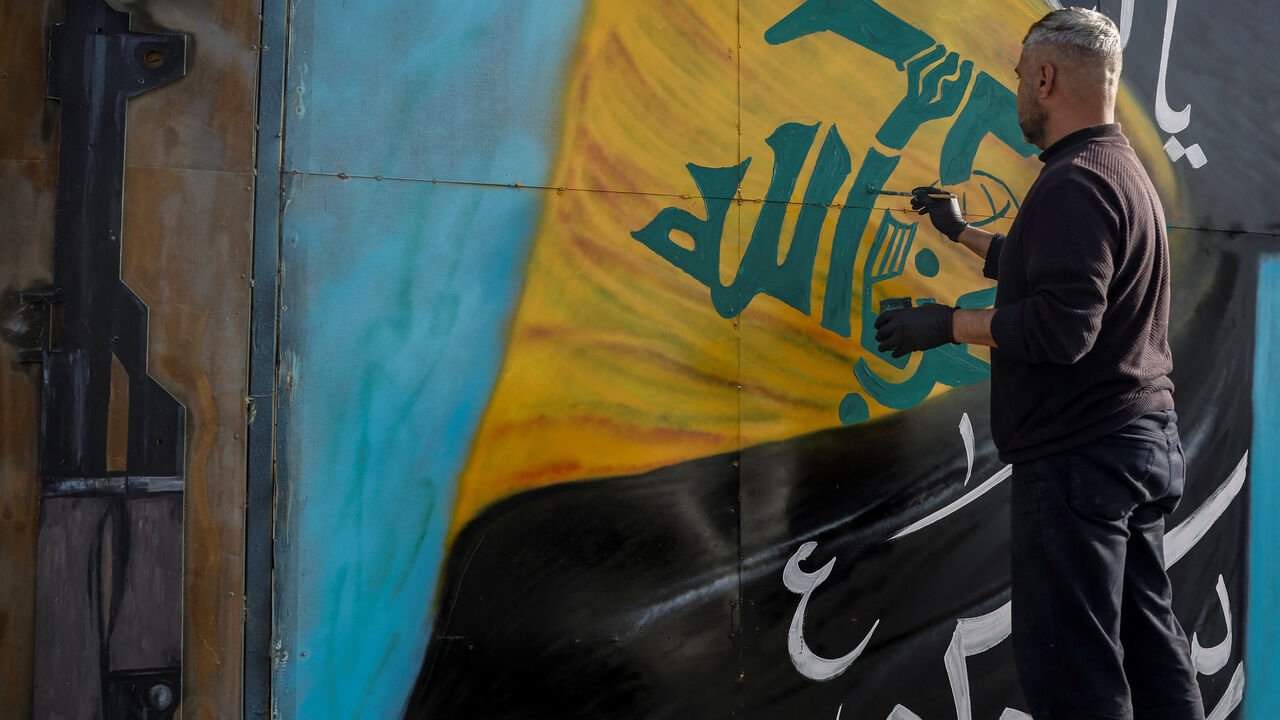 A man paints a Hezbollah flag on a board, in Tyre, south Lebanon, April 14, 2026. REUTERS/Louisa Gouliamaki