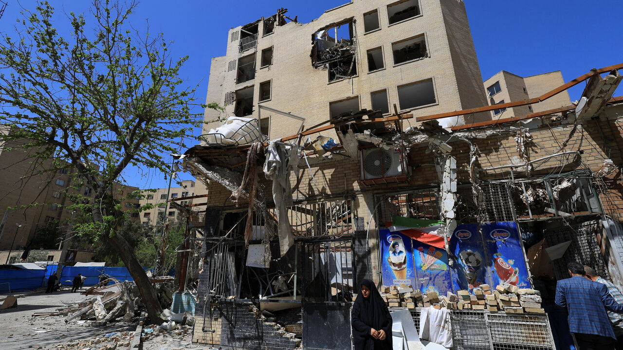 A woman stands next to debris lying in front of a residential building damaged by a strike on March 4, in Tehran, Iran, April 14, 2026. REUTERS/Thaier Al Sudani