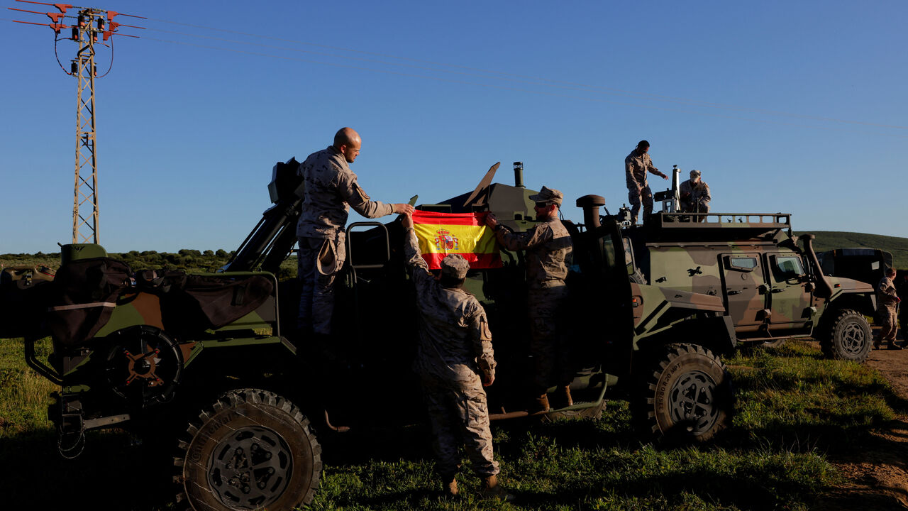 Spanish soldiers place a Spanish flag on a vehicle during Exercise Dynamic Mariner 25 military drill training, which involves naval forces from several NATO members, at Retin beach, in the Atlantic Ocean, in Barbate, Spain, March 28, 2025. REUTERS/Jon Nazca