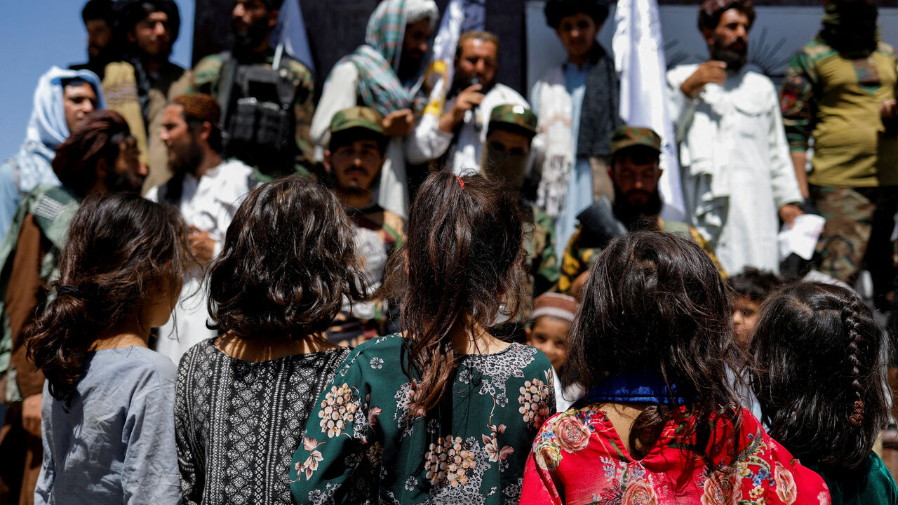 FILE PHOTO: Afghan girls look at Taliban supporters on the second anniversary of the fall of Kabul on a street near the US embassy in Kabul, Afghanistan, August 15, 2023. REUTERS/Ali Khara/File Photo