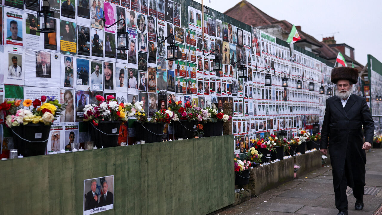 An Orthodox Jewish man walks by at a wall showing pictures of protesters killed during anti-government demonstrations in Iran, in Golders Green, London, Britain, March 7, 2026. REUTERS/Jack Taylor