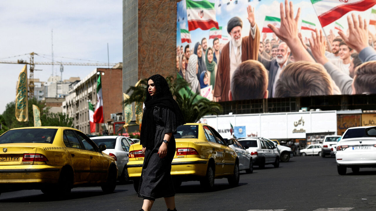 FILE PHOTO: A woman walks past a billboard featuring an image of the late Supreme Leader of Iran, Ayatollah Ali Khamenei, on a building, amid a ceasefire between U.S. and Iran, in Tehran, Iran, April 27, 2026. Majid Asgaripour/WANA (West Asia News Agency) via REUTERS/File Photo