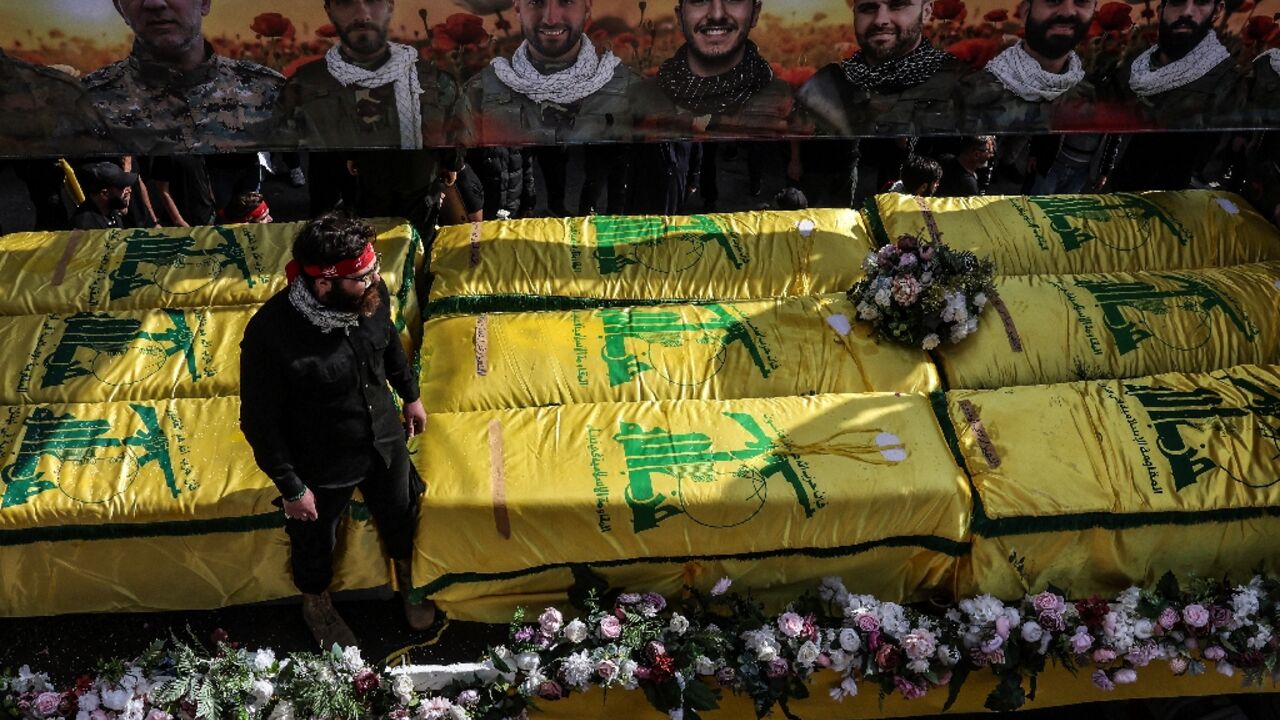 Coffins sit on a trailer beneath portraits of Hezbollah fighters killed in Lebanon by Israel before a 10-day ceasefire was agreed
