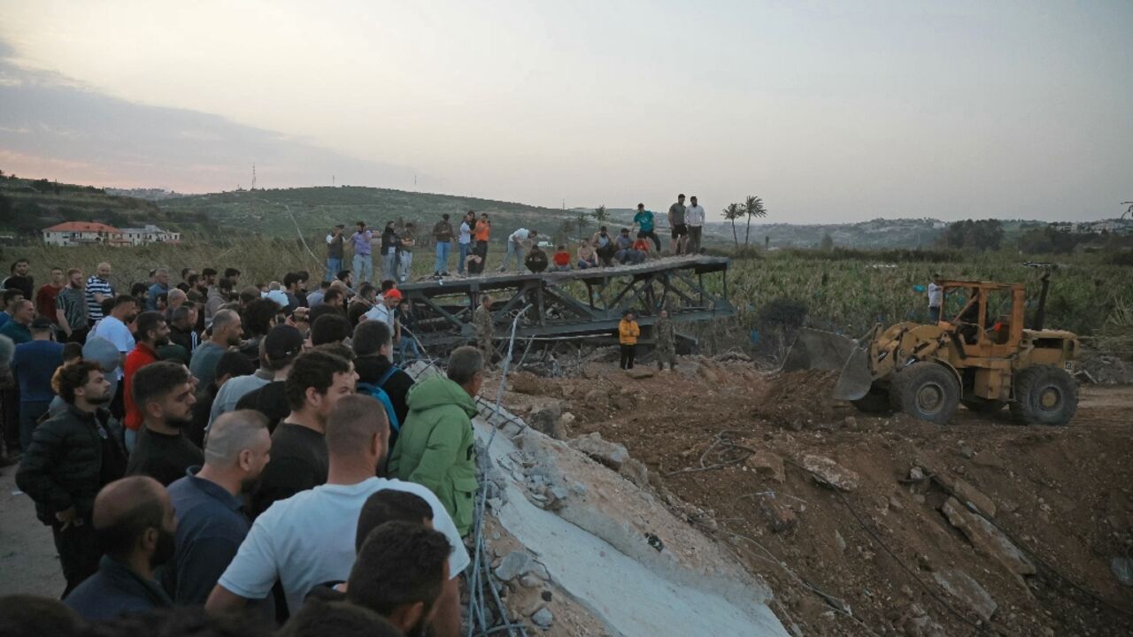 People watch as bulldozers work to reopen the Qasmiyeh bridge over the Litani River in south Lebanon