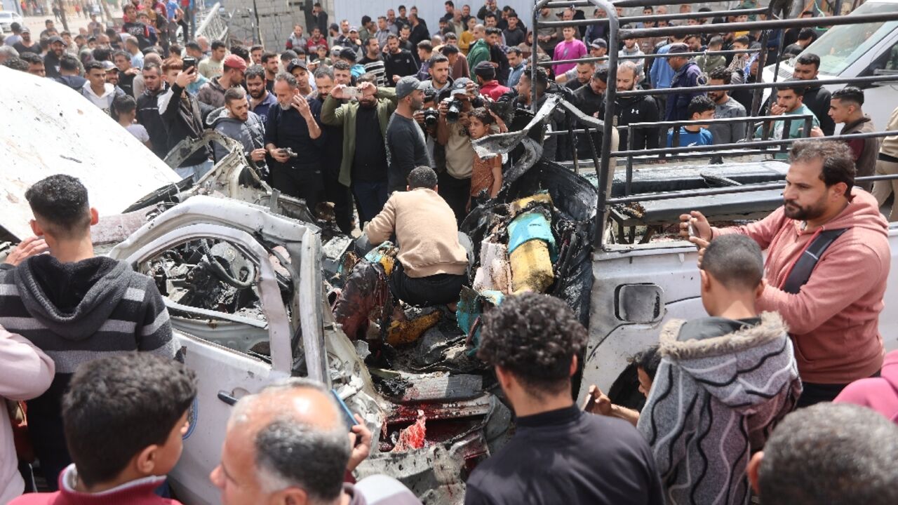Palestinians in Gaza City gather round the wreckage of the police vehicle destroyed in an Israeli strike
