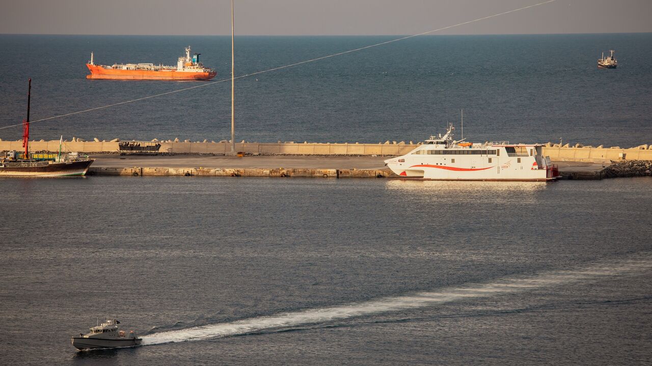 A police speedboat patrols the port as oil tankers and high-speed crafts sit anchored at Muscat Anchorage near the Strait of Hormuz on March 30, 2026, in Muscat, Oman.