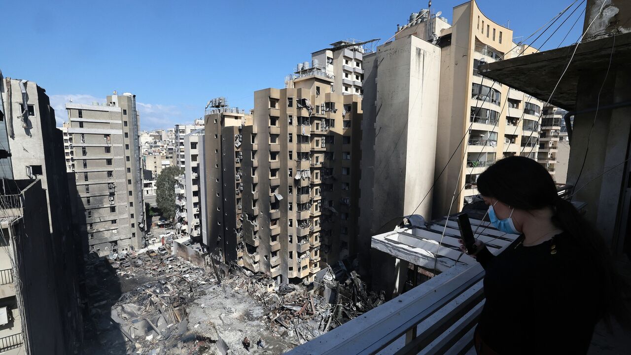 A woman takes a picture with her mobile phone of Lebanese first responders searching under the rubble at the site of an Israeli airstrike that targeted a building the day before in Beirut's Corniche al-Mazraa neighborhood, on April 9, 2026. 