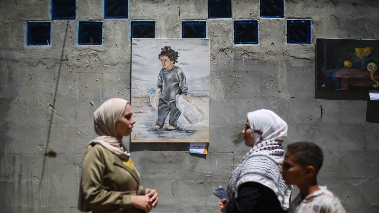 Displaced Palestinian people look at paintings at an open-air art exhibition at the Bureij camp for Palestinian refugees in the central Gaza Strip on April 28, 2026. The majority of Gaza's 2.4 million people have been displaced, often multiple times, by the war that began with Hamas's attack on southern Israel on October 7, 2023. With displaced families living in tented camps, with serious concerns raised about their living conditions. (Photo by Eyad Baba / AFP via Getty Images) / -- IMAGE RESTRICTED TO EDI