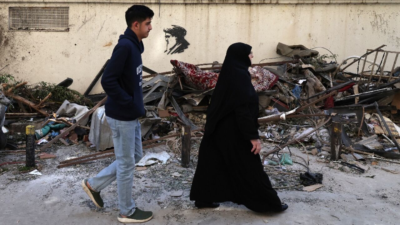 Residents walk past scattered debris at the site of an Israeli airstrike in the Lebanese capital Beirut