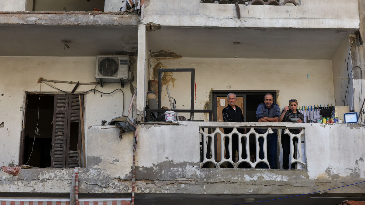 People sit on a balcony near the site of an Israeli strike that took place before a temporary ceasefire went into effect, on the southern suburbs of Beirut, Lebanon, May 6, 2026. REUTERS/Mohamed Azakir