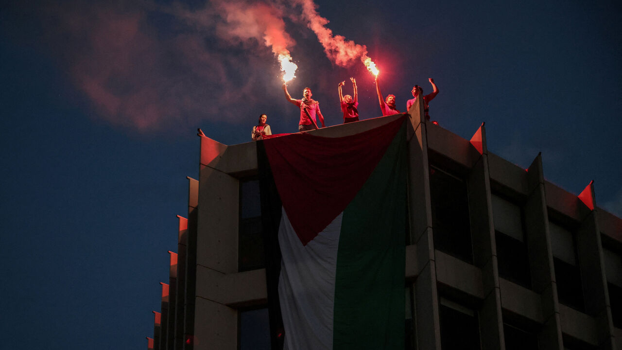 Protesters who hung a huge Palestinian flag at a building facing the Israeli embassy, lit flares during a protest over the interception of the Gaza aid flotilla, in Athens, Greece, May 21, 2026. REUTERS/Louisa Gouliamaki