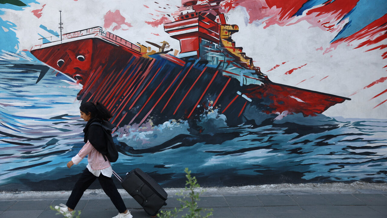 An Iranian woman walks next to a mural on a street in Tehran, Iran, May 11, 2026. Majid Asgaripour/WANA (West Asia News Agency) via REUTERS