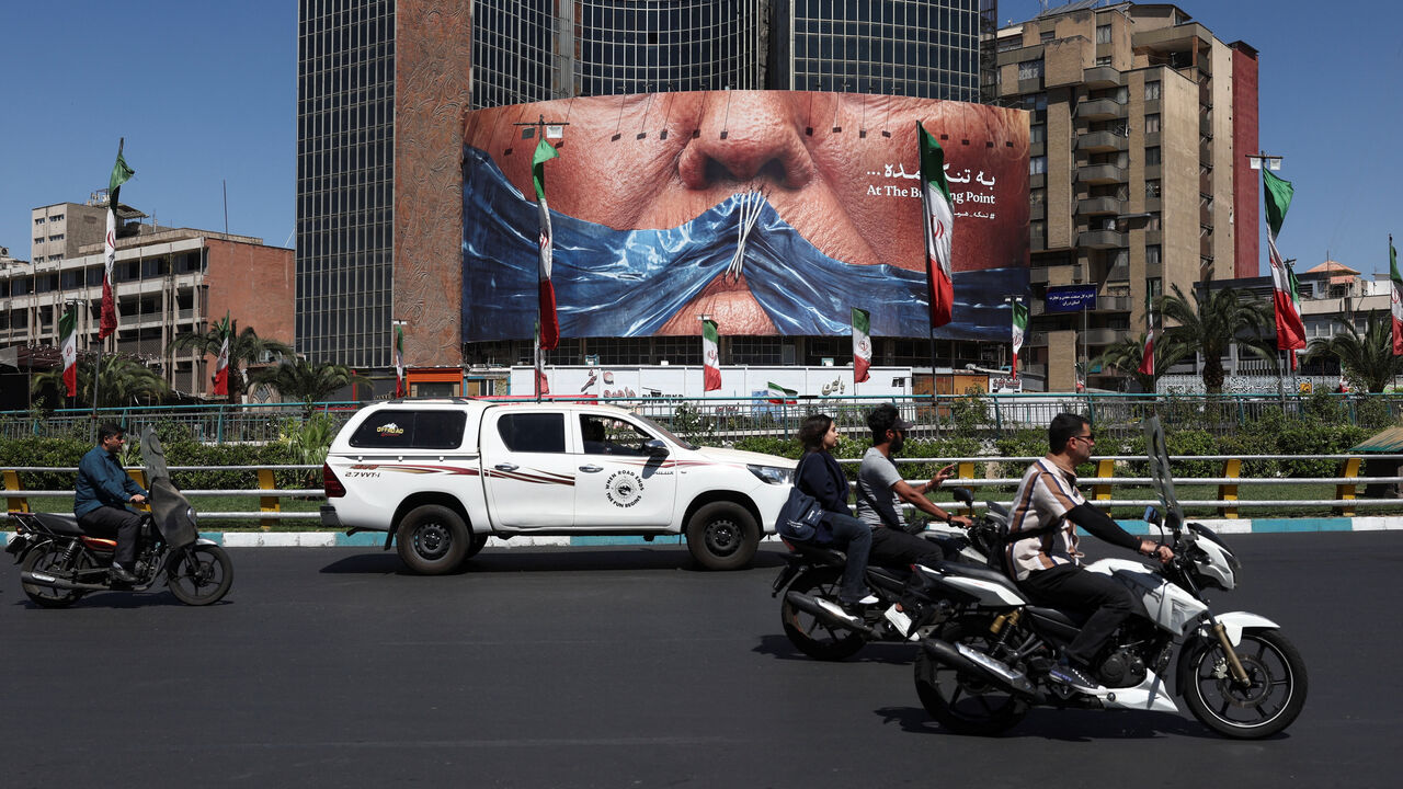 People ride past an anti-U.S. billboard depicting U.S. President Donald Trump and the Strait of Hormuz, in Tehran, Iran, May 25, 2026. Majid Asgaripour/WANA (West Asia News Agency) via REUTERS