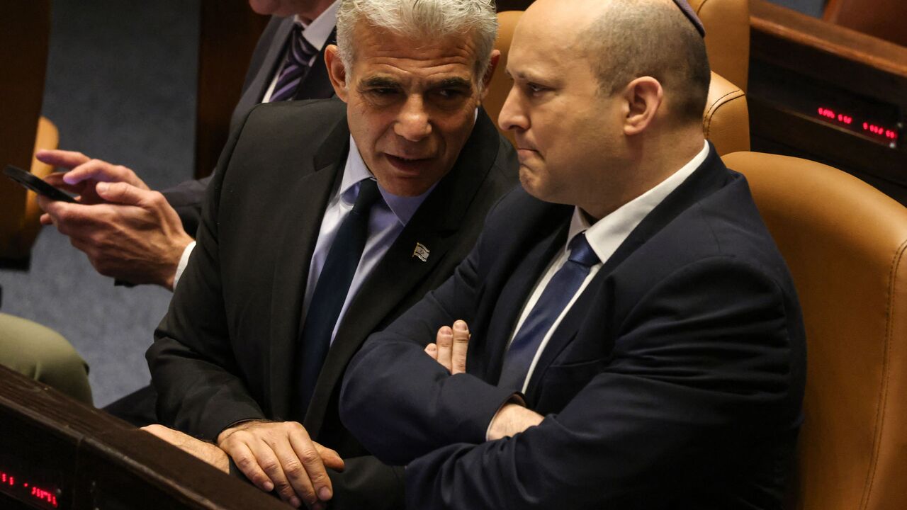 Israeli Minister of Foreign Affairs Yair Lapid (L) speaks to outgoing Prime Minister Naftali Bennett, during a meeting at the Knesset (parliament), in Jerusalem on June 30, 2022. - Final approval of the parliament dissolution bill was initially expected by midnight but was postponed to June 30 as coalition and opposition lawmakers sparred over last-minute legislative details, several sources familiar with the parliamentary said. (Photo by Menahem KAHANA / AFP) (Photo by MENAHEM KAHANA/AFP via Getty Images)