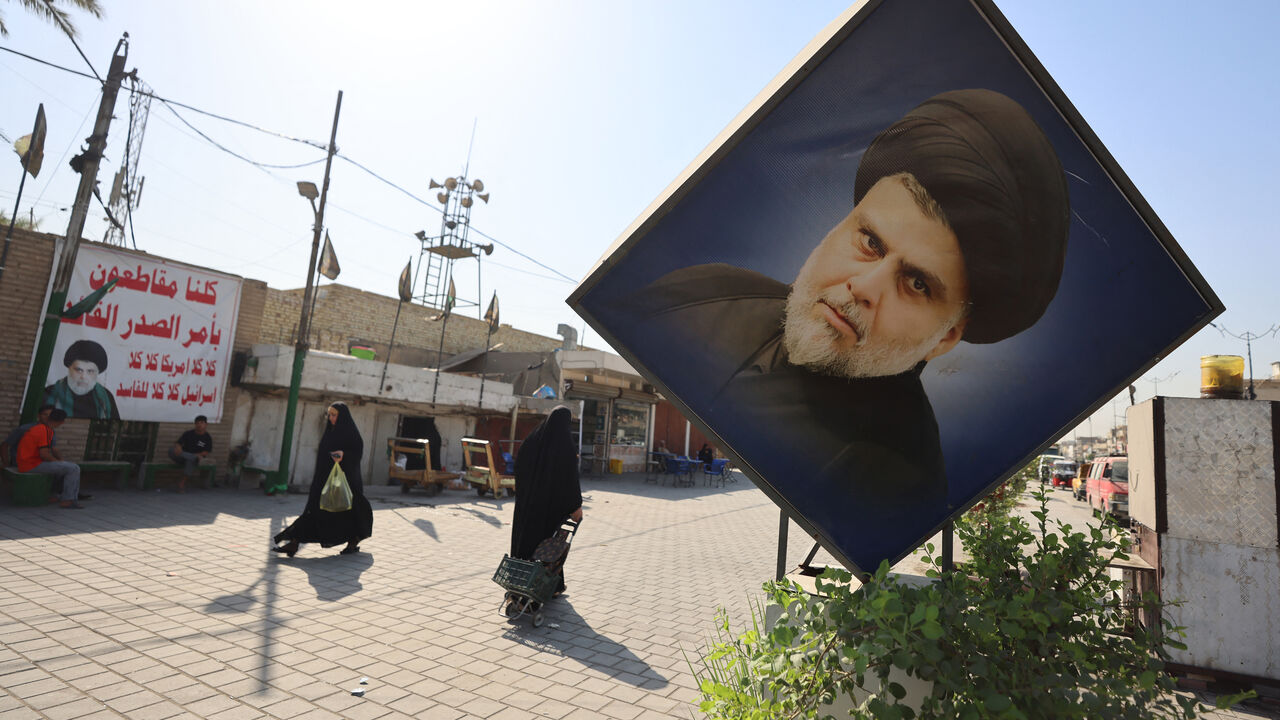 Iraqis walk past portraits of Iraqi Shiite cleric Muqtada al-Sadr, including one on a banner calling for a boycott of the upcoming parliamentary elections in Sadr City, east of Baghdad on October 29, 2025. Parliamentary elections are scheduled to be held in Iraq on 11 November 2025, which will determine the 329 members of Iraq's Council of Representatives, who are responsible for electing the country's president and approving the appointment of the prime minister. (Photo by AHMAD AL-RUBAYE / AFP) (Photo by 
