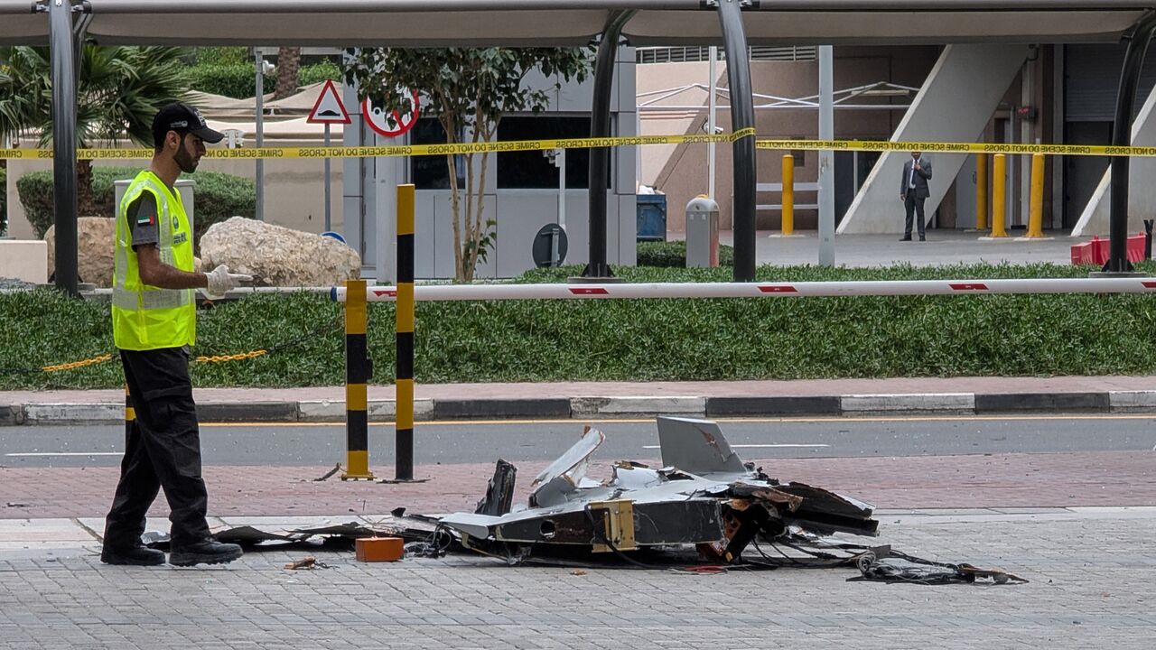 A policeman inspects the wreckage of a drone in downtown Dubai on March 12, 2026. 