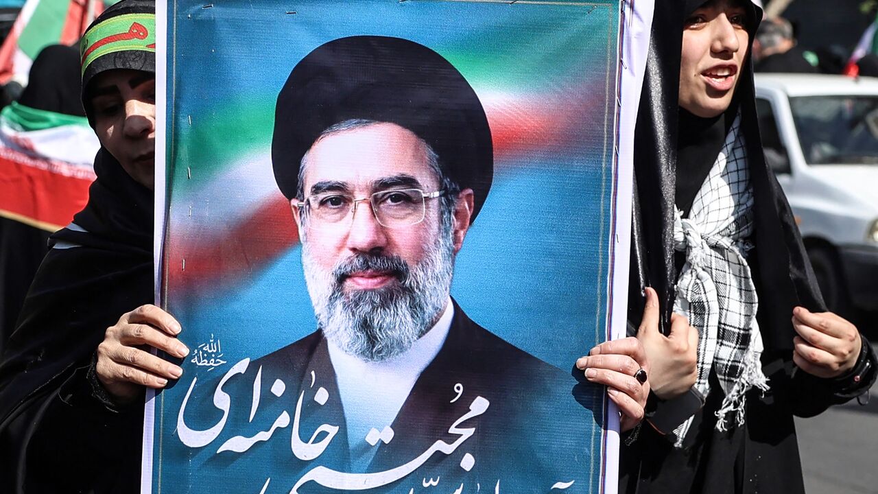 An Iranian woman holds up an image of Iran's new supreme leader Ayatollah Mojtaba Khamenei.