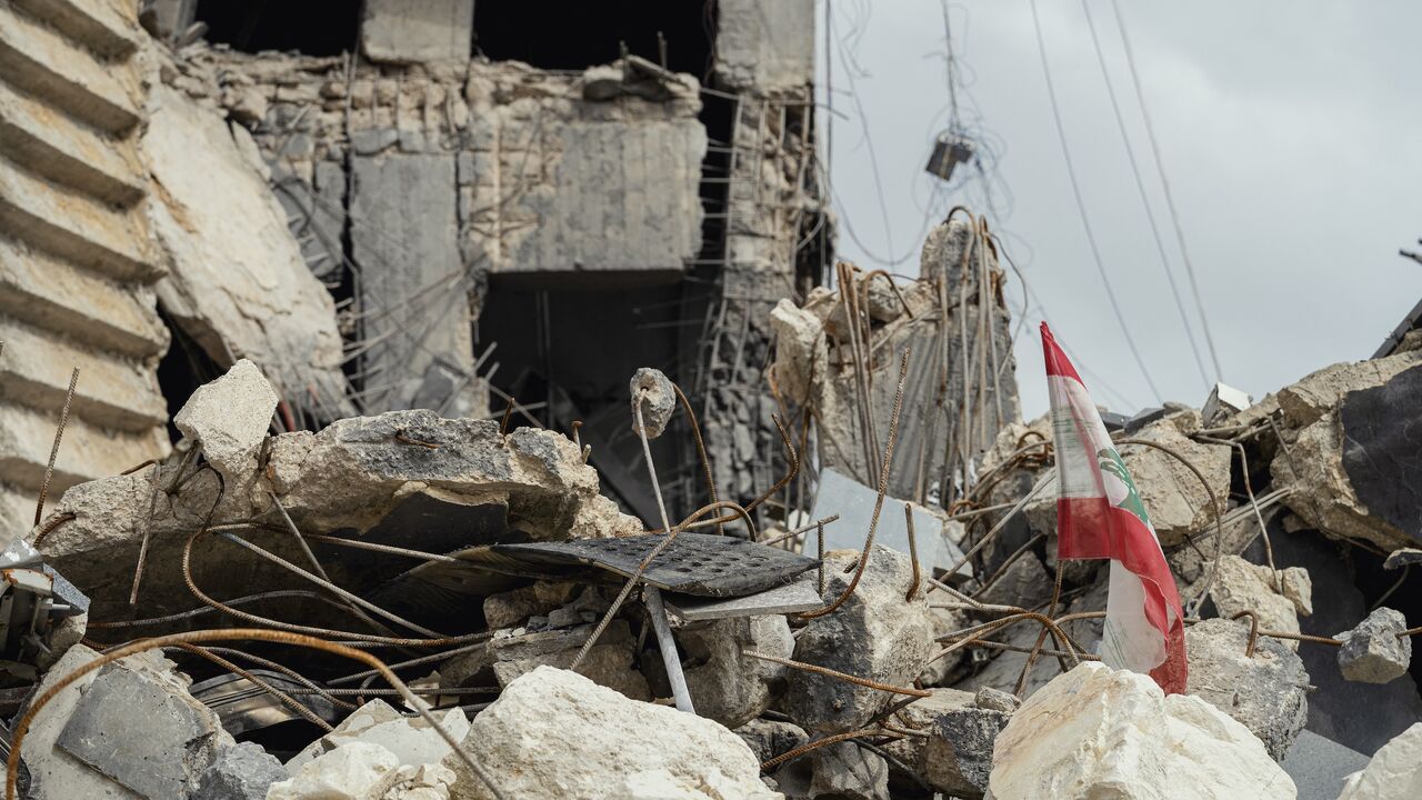 A view shows a Lebanese flag positioned among shattered concrete and twisted rebar, remnants of a destroyed building, in Sidon, Lebanon, on May 3, 2026. 