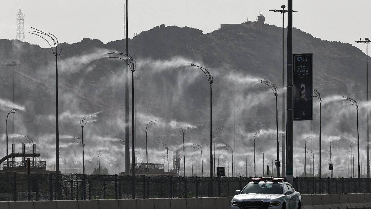 A police car drives past water-mist fans in Mecca ahead of the hajj pilgrimage when temperatures could reach 47 degrees Celsius