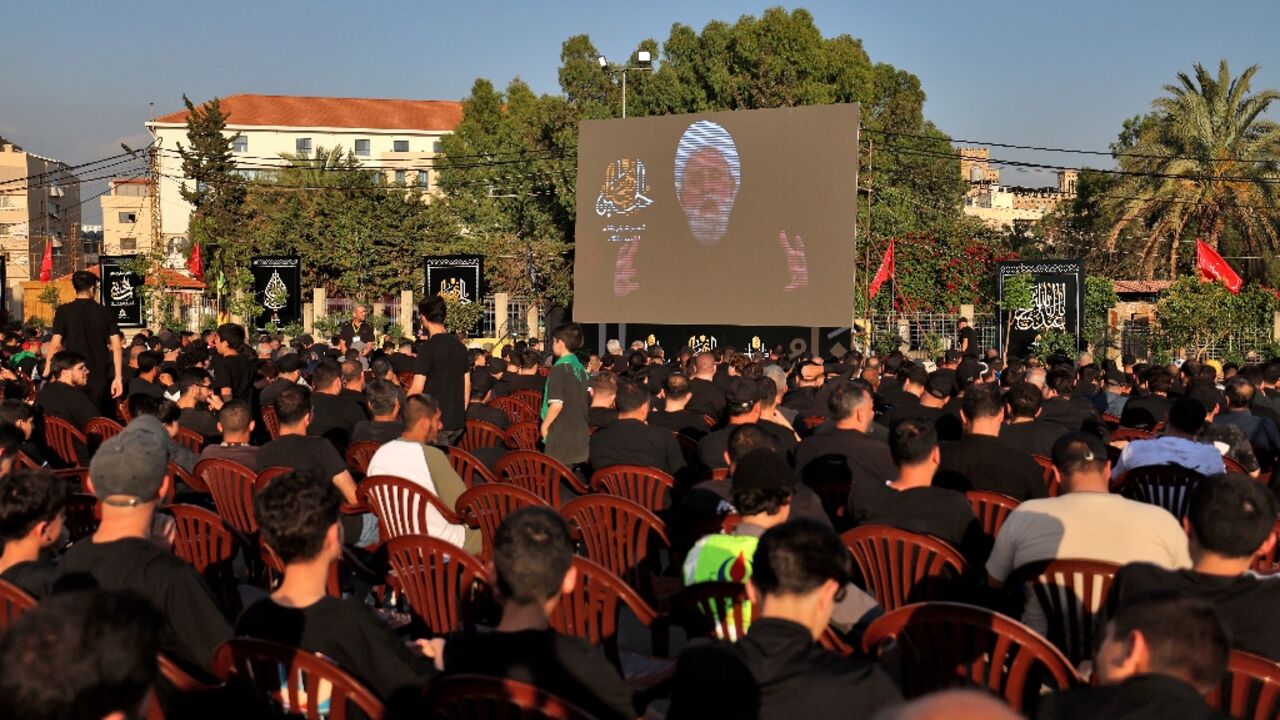Hezbollah Secretary-General Sheikh Naim Qassem addresses crowds via a giant screen during the first day of Ashura commemorations at the mausoleum of former Hezbollah leader Hassan Nasrallah in Beirut’s southern suburbs
