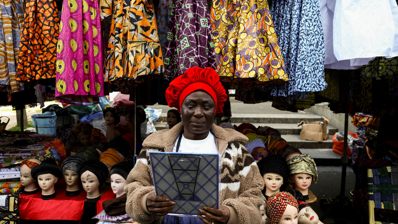 A woman tries on a new hat in the 800 metre-long Tuesday Market in Sarcelles, which has vendors selling food, clothing, homeware products and handicrafts to cater for Sarcelles' diverse immigrant community in the Paris suburb of Sarcelles, France, April 14, 2026. REUTERS/Tom Nicholson