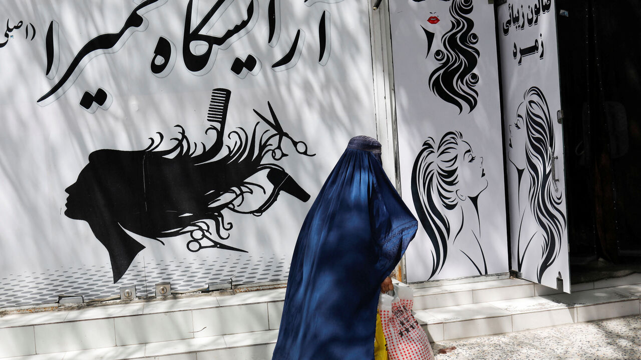 An Afghan woman walks past a beauty salon in Kabul, Afghanistan, July 6, 2023. REUTERS/Ali Khara/File Photo
