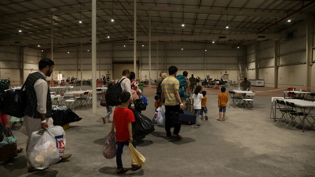 Special Immigrants from Afghanistan walk through the in-processing building after their evacuation at Camp As Sayliyah, Qatar, August 20, 2021. U.S. Army/Sgt. Jimmie Baker/Handout via REUTERS