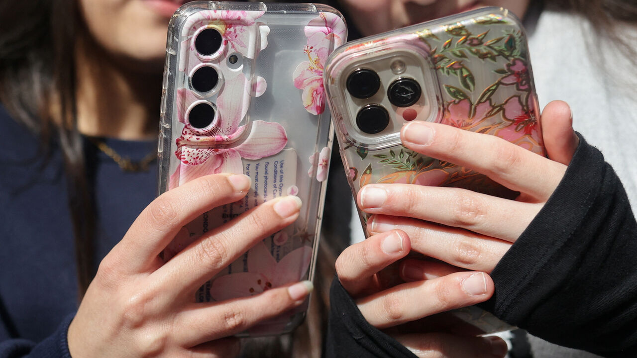 Students Dua, 16 and Awand, 17, from Ricards Lodge High School in Wimbledon pose holding their mobile phones during an interview and discussion with Reuters about their thoughts on a social media ban for under 16s, in London, Britain, February 23, 2026, REUTERS/Katie Collins
