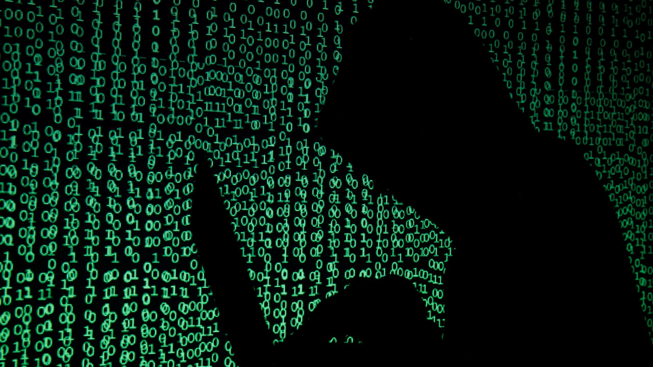 A hooded man holds a laptop computer as cyber code is projected on him in this illustration picture taken on May 13, 2017. REUTERS/Kacper Pempel/Illustration