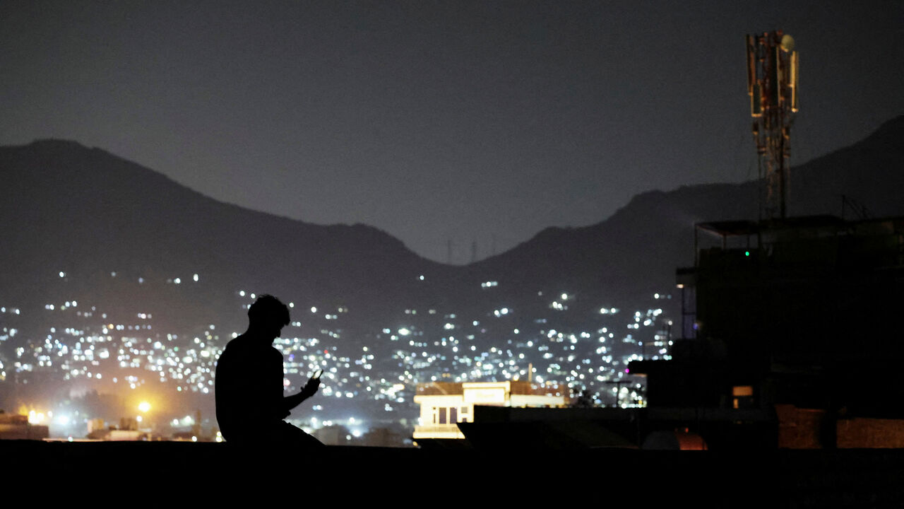 FILE PHOTO: A man sits on a wall while talking to someone on a video call in Kabul, Afghanistan, October 1, 2025. REUTERS/Sayed Hassib/File Photo