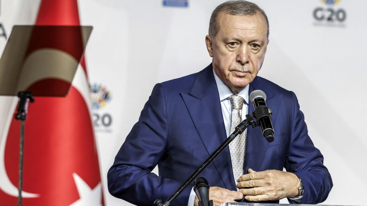 Turkey's President Recep Tayyip Erdogan buttons up his jacket during a press conference after the conclusion of the G20 Leaders' Summit at the Nasrec Expo Centre in Johannesburg on November 23, 2025. 