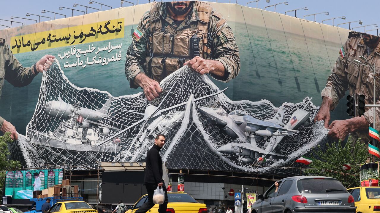 Vehicles drive past a giant billboard reading 'The Strait of Hormuz remains closed' at the Revolution Square in Tehran on April 28, 2026