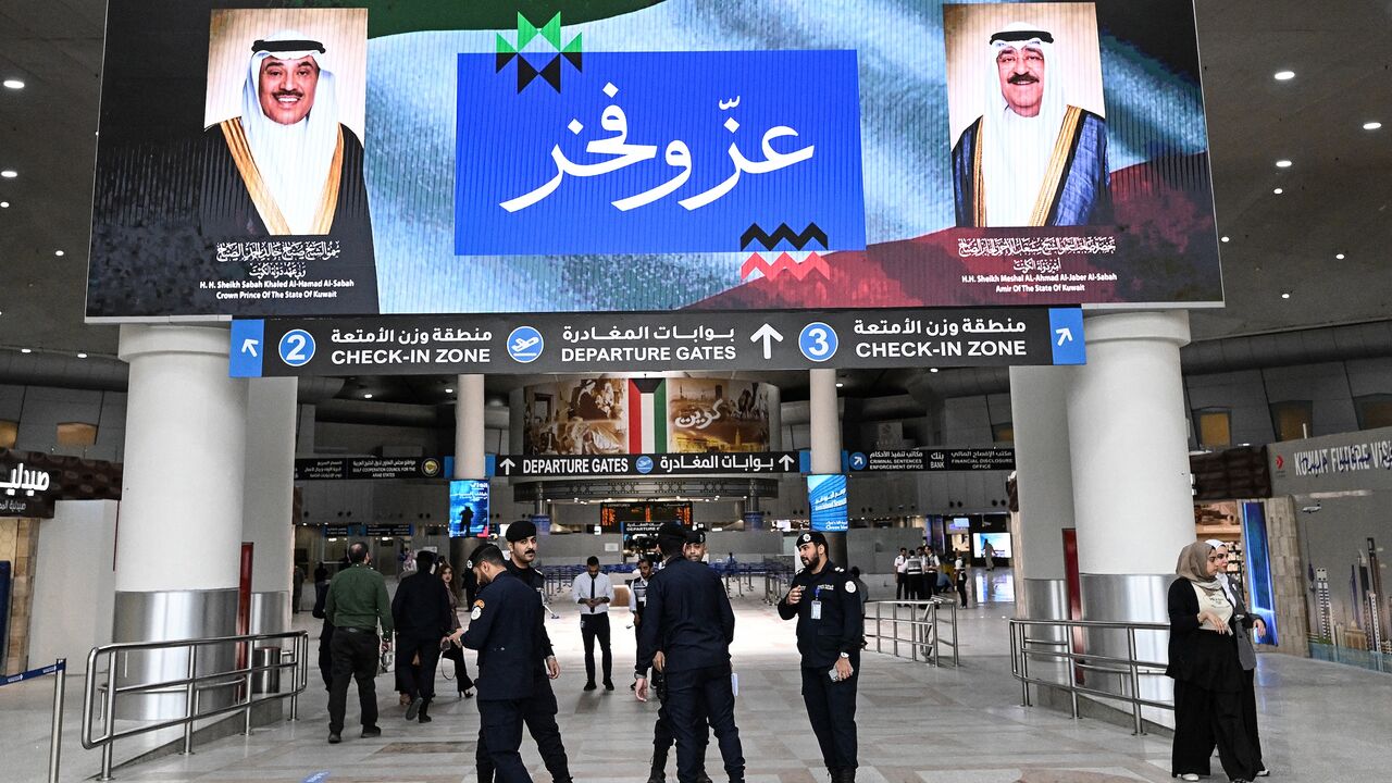 Kuwaiti security officers stand beneath a screen displaying portraits of the Emir of Kuwait Sheikh Meshal al-Ahmad al-Jaber al-Sabah (R) and the Kuwaiti crown prince Sheikh Sabah al-Khaled al-Hamad al-Sabah, alongside the words "Pride and Glory", at Kuwait International Airport in Kuwait City on June 1, 2026, as the airport resumes operations following a phased reopening plan. 