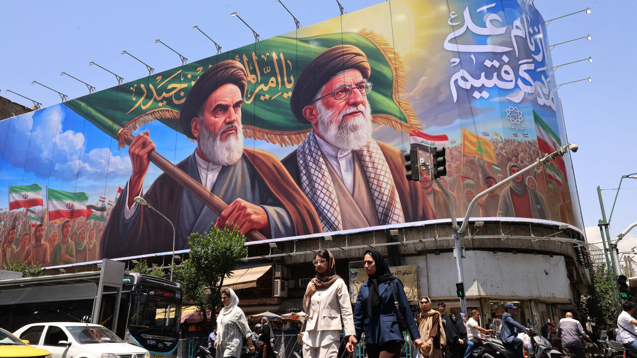 TOPSHOT - People cross the street past a large billboard showing portraits of Iran's late supreme leader, Ayatollah Ruhollah Khomeini (L) and slain supreme leader Ayatollah Ali Khamenei (R) in central Tehran on June 8, 2026. Iran said on June 8 that the resumption of hostilities in the Middle East war will have consequences for ongoing talks with the United States to reach peace in the region. "It is perfectly natural that the diplomatic process initiated to put an end to this imposed war would be affected,