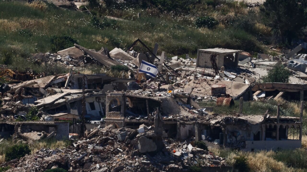 An Israeli flag is seen on top of a destroyed building in the southern Lebanese village of Kfar Kela near the two countries' shared border 