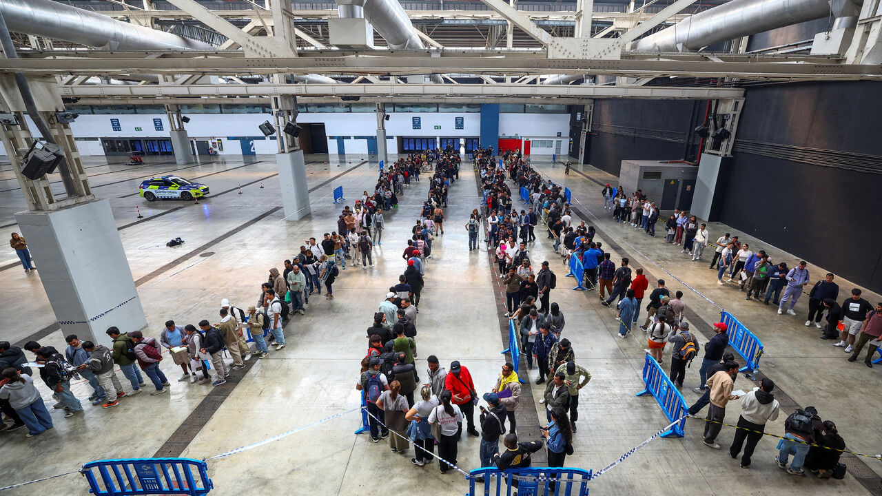 FILE PHOTO: People queue to receive documentation as Spain's mass migrants regularisation process is set to start, in Hospitalet de Llobregat, near Barcelona, Spain, April 20, 2026. REUTERS/Albert Gea/File Photo