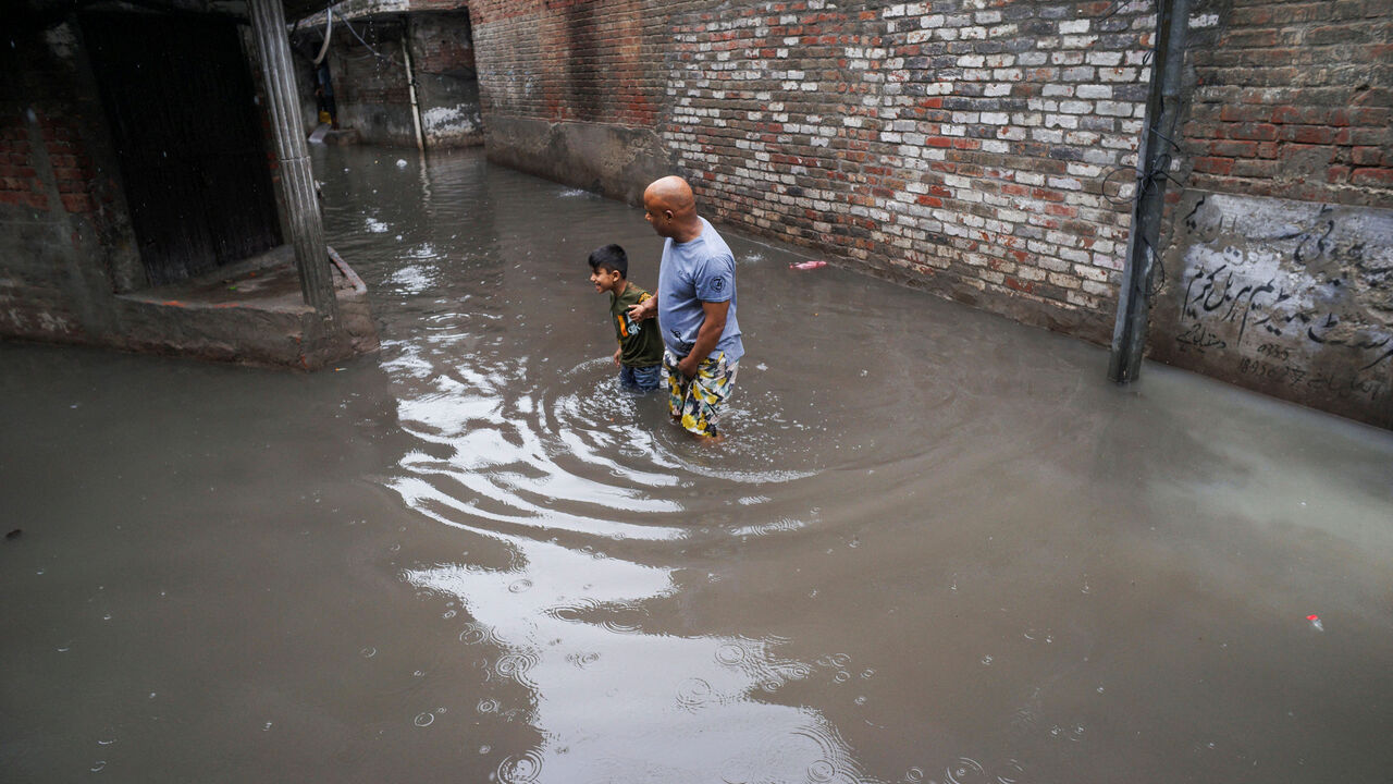 A man and a boy wade through a flooded street amid rain in Gujranwala, Pakistan, July 23, 2026. REUTERS/Syed Aftab Rizvi