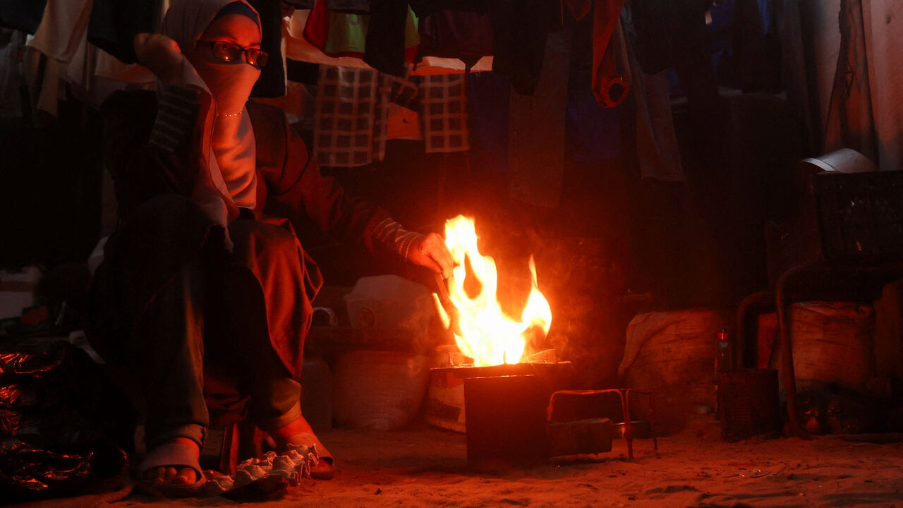 Displaced Palestinian woman Dunya Abu Taima lights a cooking fire amid shortages of lighters and cooking gas, in Khan Younis, in the southern Gaza Strip, July 21, 2026. REUTERS/Ramadan Abed