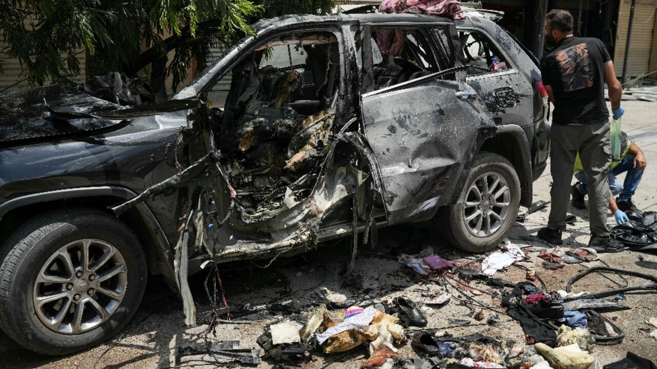 First responders inspect the wreckage of a car reportedly targeted by an Israeli strike in Nabatieh in southern Lebanon