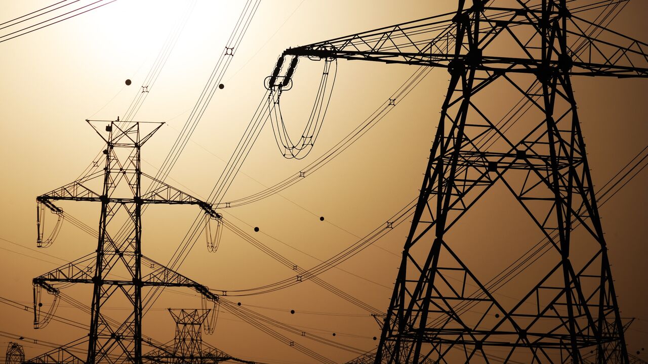 The sun sets behind overhead power lines in Kuwait City, June 19, 2024.