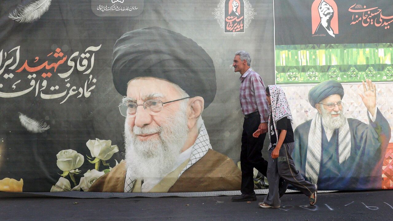 Iranians walk past a billboard bearing a picture of Iran's slain supreme leader Ali Khamenei ahead of his funeral in Tehran on July 3, 2026. Iranian leaders began paying their respects on July 3 before the coffin of the country's late supreme leader Ali Khamenei, killed in the US-Israeli strikes that triggered the Middle East war, as Tehran prepared for a vast funeral. Khamenei's body arrived at Tehran's Grand Mosalla on July 3 ahead of ceremonies which are expected to draw millions. (Photo by AFP via Getty