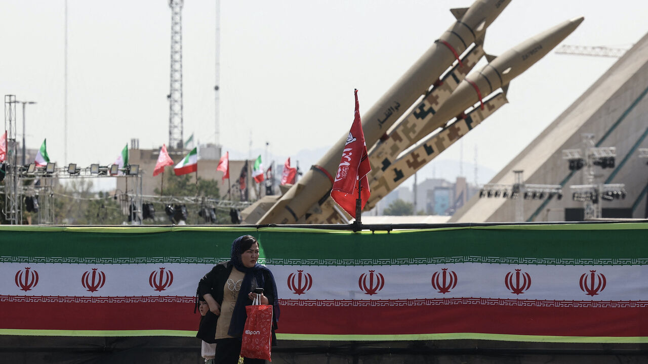 A woman stands next to Iranian-made Zolfaghar missiles displayed at Azadi Square in Tehran on July 24, 2026. 