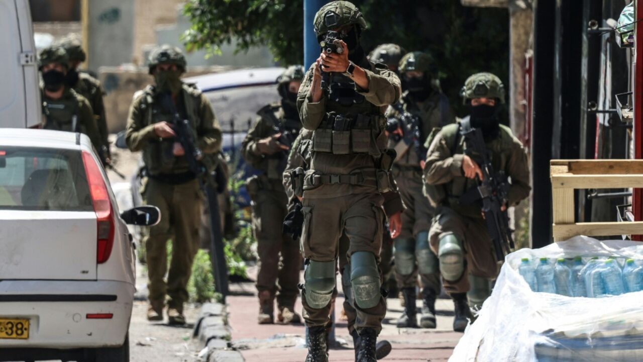 A member of the Israeli security forces aims his weapon while patrolling along a street during a military raid in the Qalandia refugee camp, south of Ramallah in the Israeli-occupied West Bank