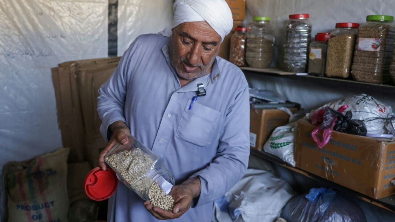 Salem Muhanna, who manages the Al Qarara Seed Bank with support from the ICRC, displays white cowpea seeds at the bank, in Deir el-Balah, central Gaza Strip