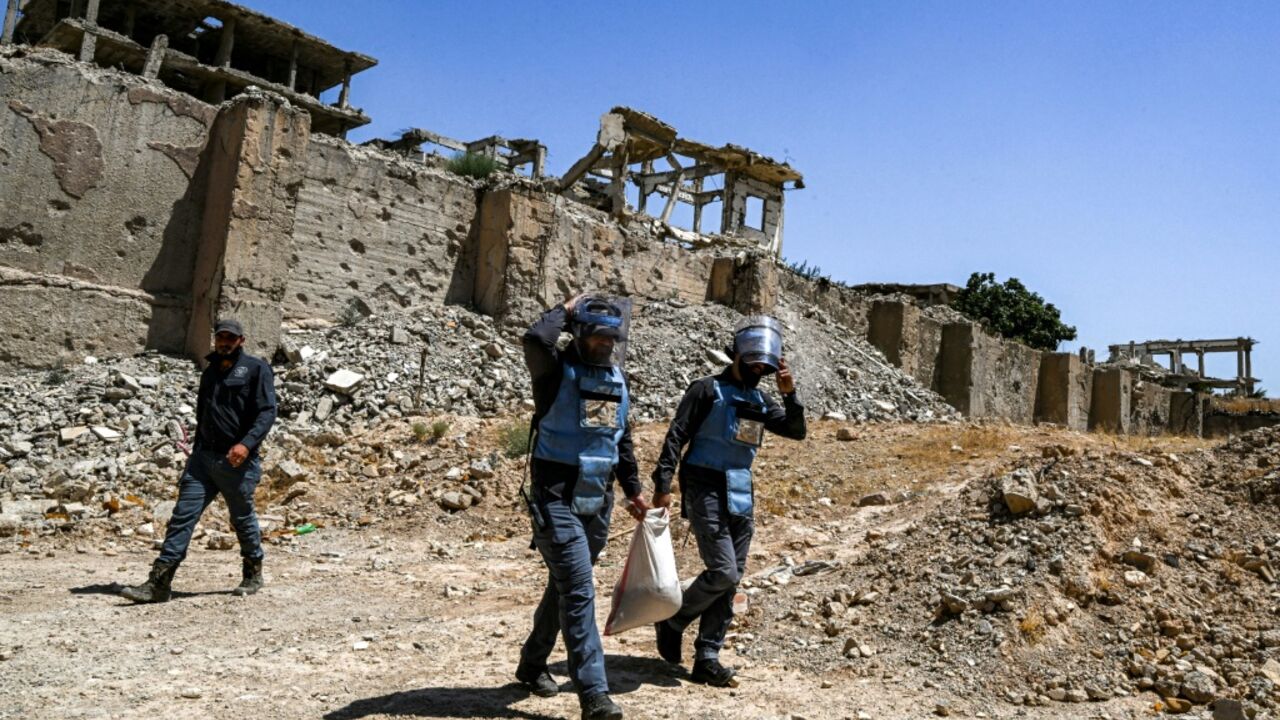 Members of a humanitarian NGO work to clear landmines and other explosive devices prepare to detonate unexploded war-remnants in a suburb of Damascus, Syria