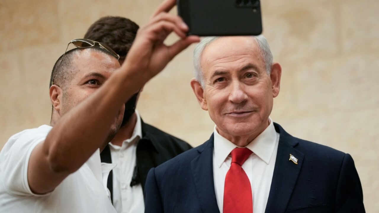 Israeli Prime Minister Benjamin Netanyahu takes a selfie with a supporter as he arrives to cast his ballot during his Likud party's primary elections on August 17, 2026