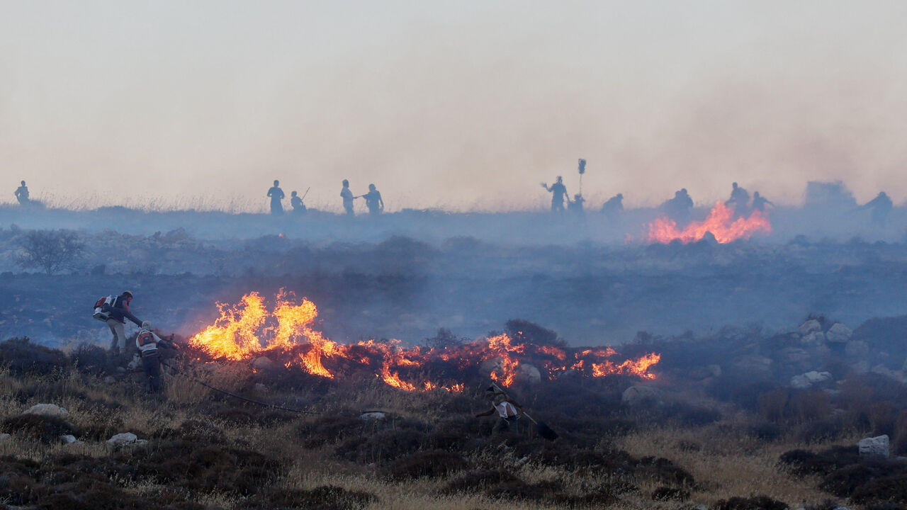 Israeli settlers put out a fire by a settler outpost, near the Palestinian town Taybeh in the Israeli-occupied West Bank, July 17, 2026. REUTERS/Ammar Awad