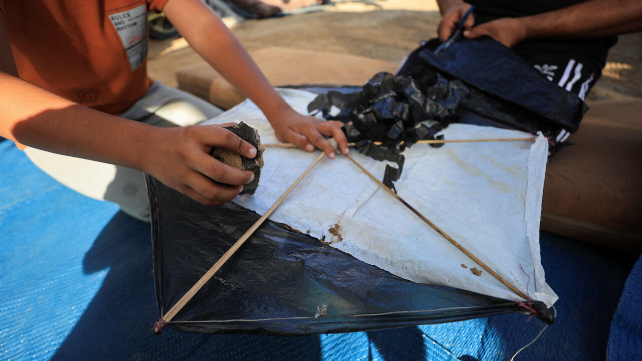 Palestinians make a kite at a tent camp sheltering displaced people in Gaza City, August 25, 2026. REUTERS/Dawoud Abu Alkas
